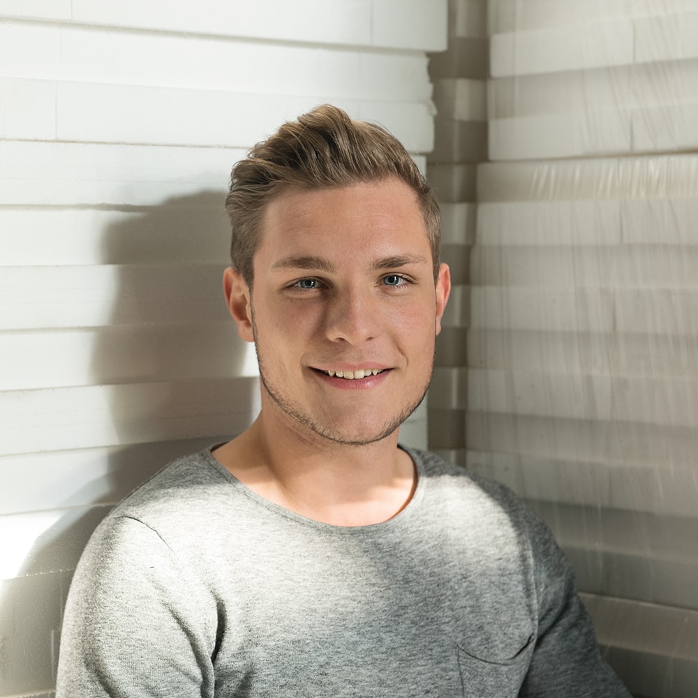 blonder, lächelnder Mann mit grauem T-Shirt